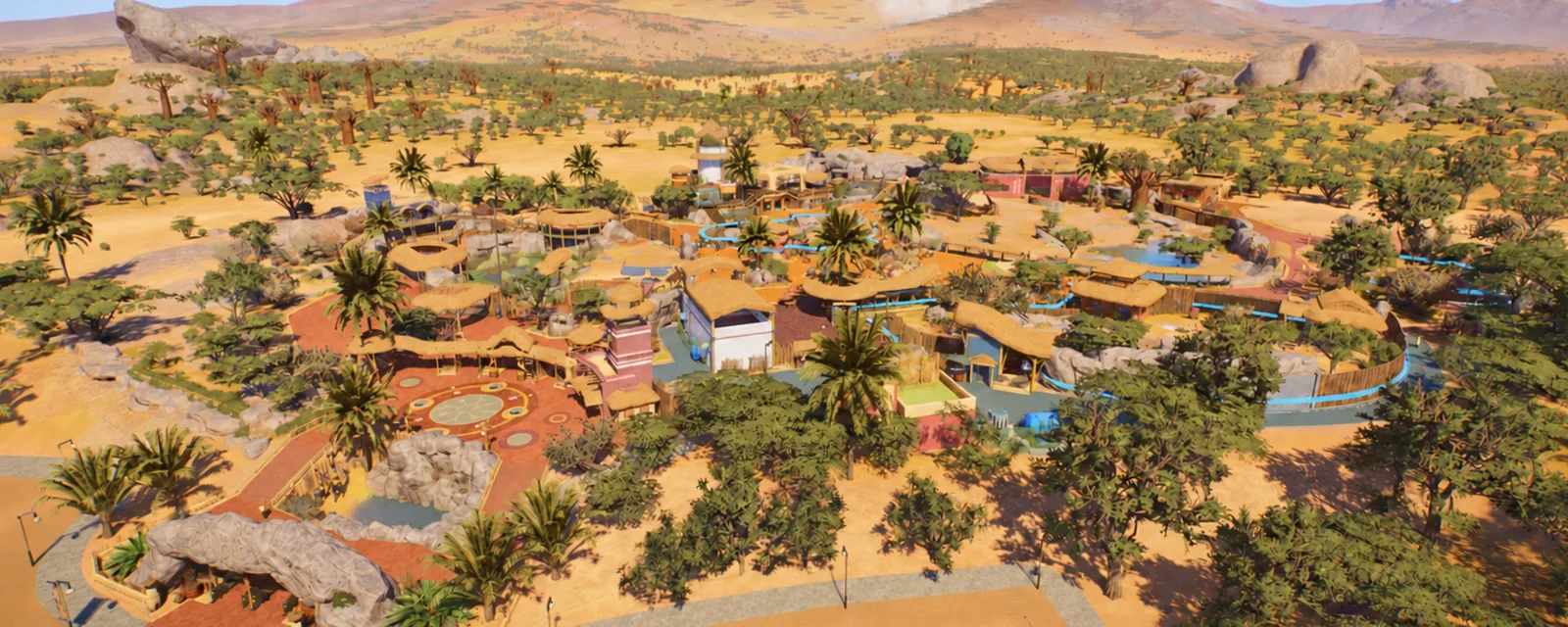 A zoo entrance built around a rock arch, with paths and habitats stretching toward the mountains